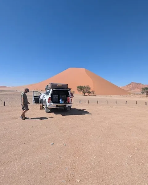 Clients stopping with their Namib Trails 4x4 in front of a giant sand dune in Namibia